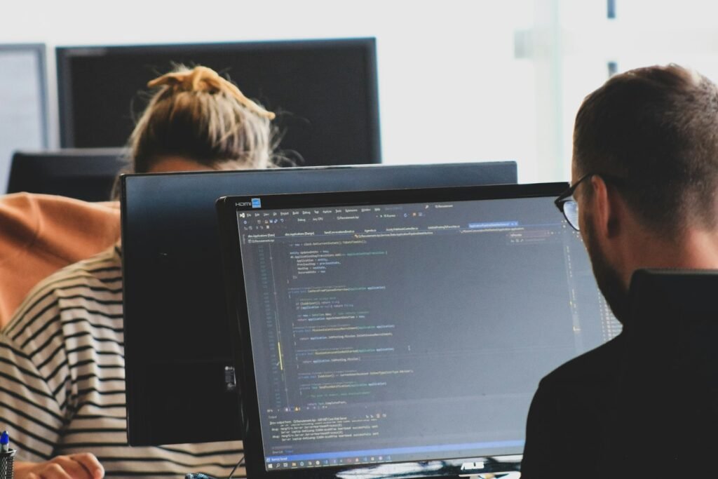Software QA services engineers reviewing and testing code on monitors